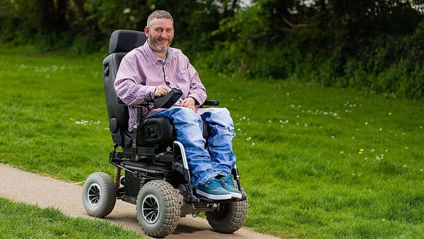 Steven Webb in electric wheelchair bluejeans pink top
